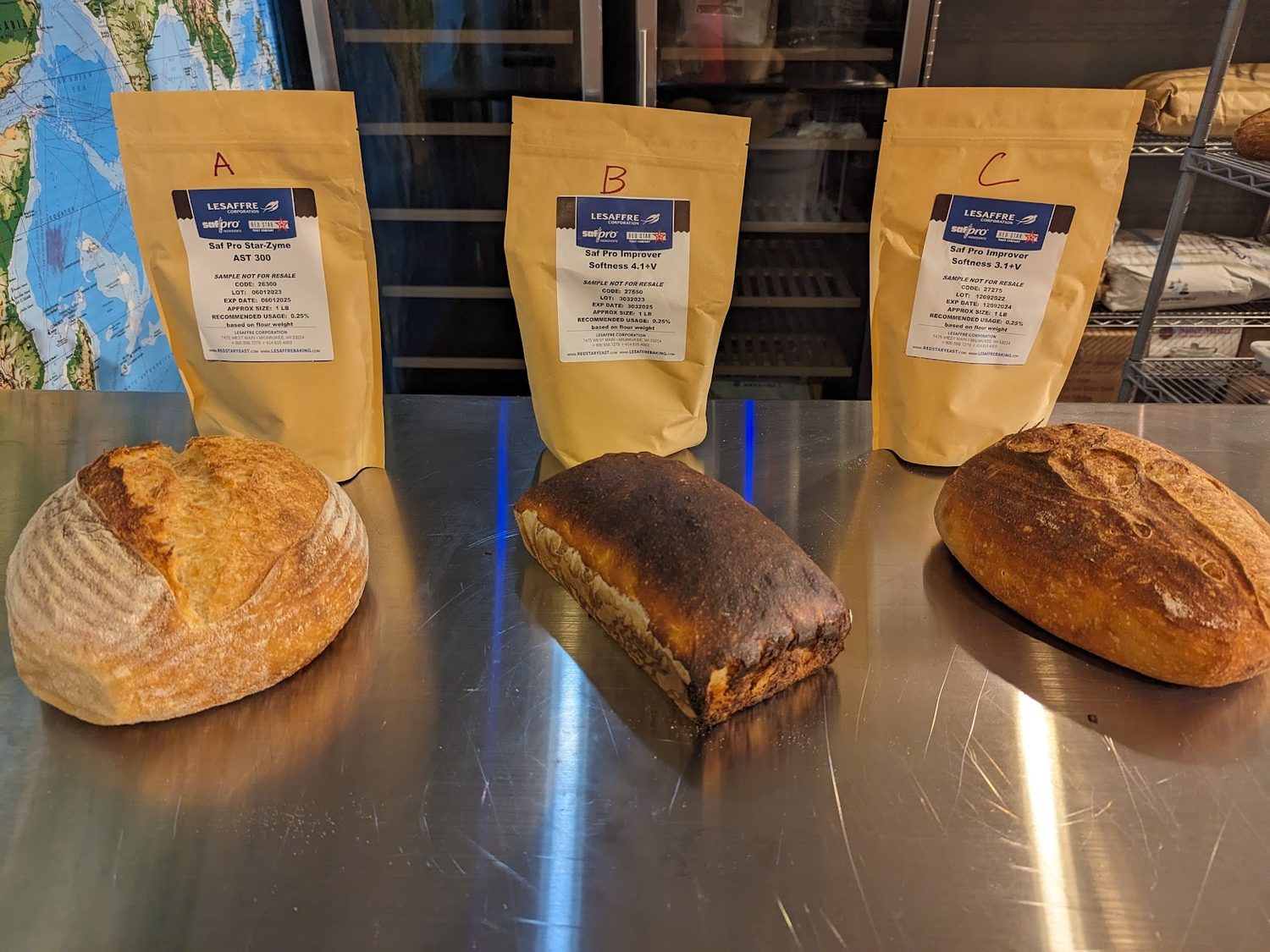 Three loaves labelled A, B and C in front of three sample bags of commercial dough enzymes