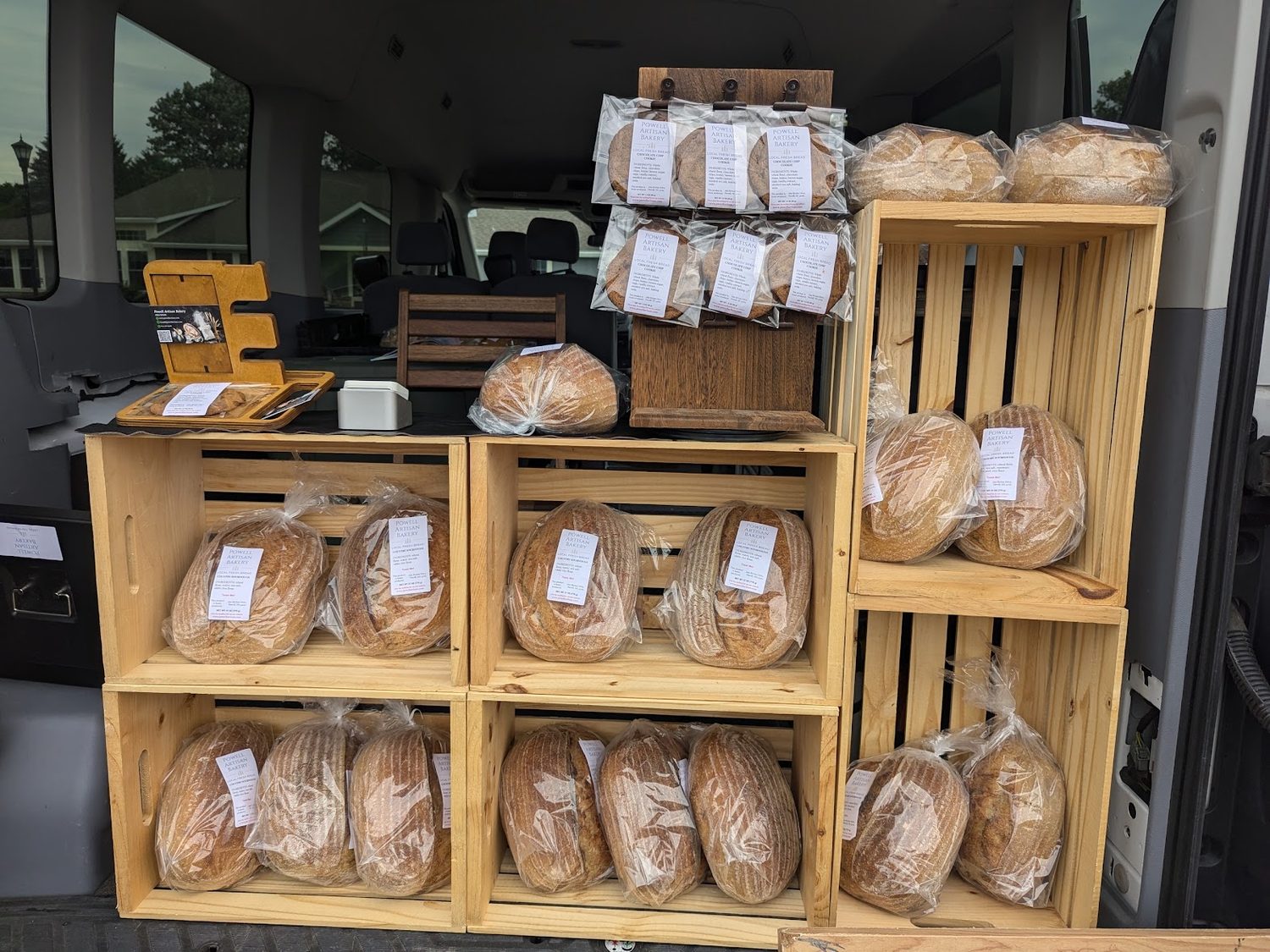 Crates of bagged sourdough loaves and cookies arranged on wooden crates inside the van