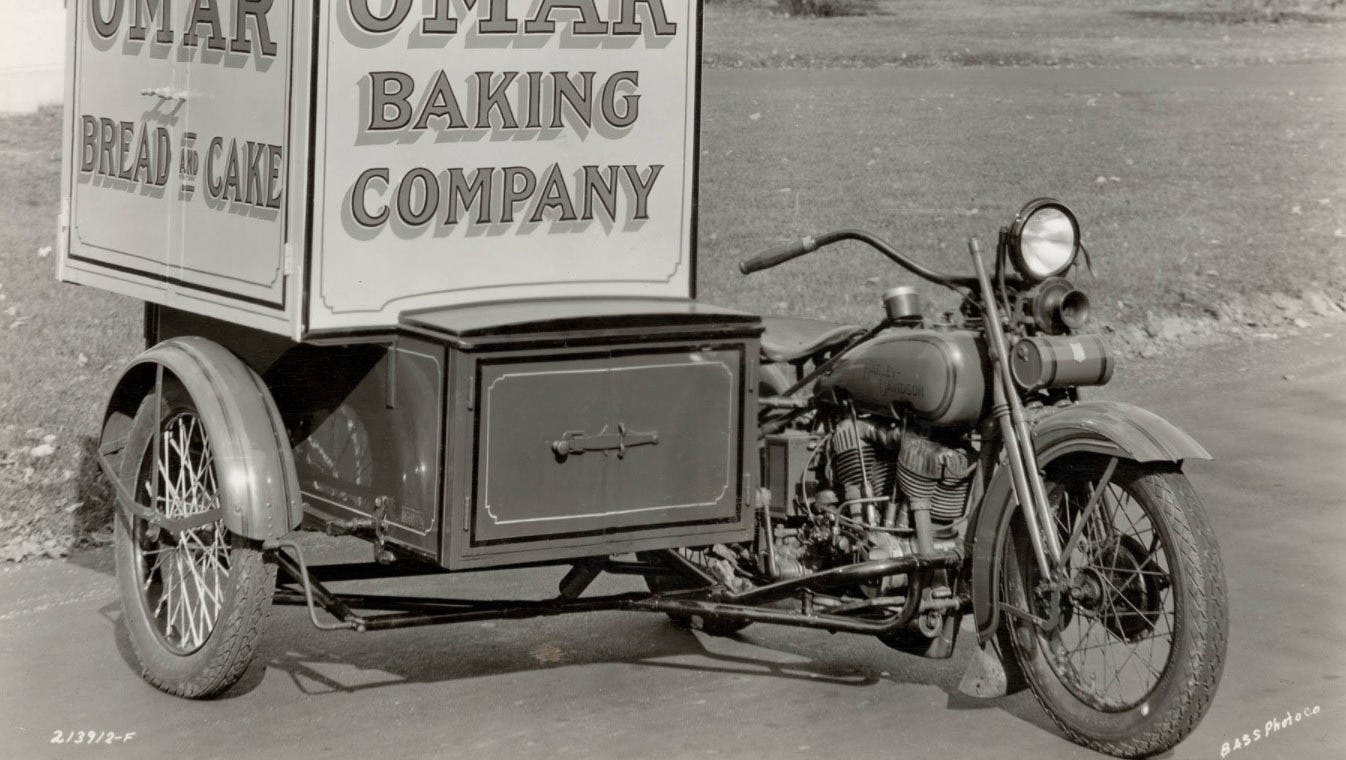 An archival photograph of a Harley-Davidson delivery trike with a box body lettered Omar Baking Company, Bread and Cake